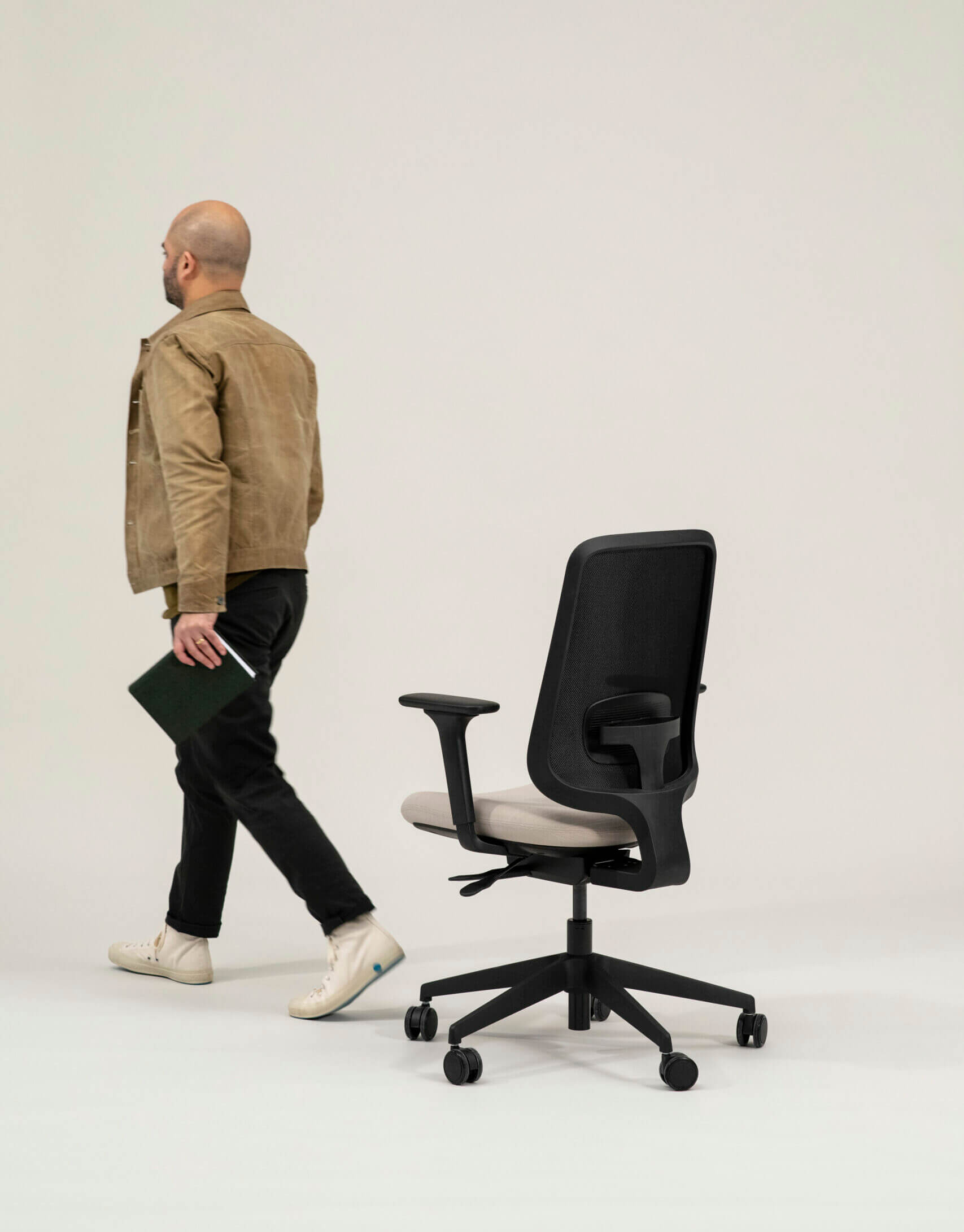 A Person Walking Away From a Task One Black Frame Office Chair With Arms