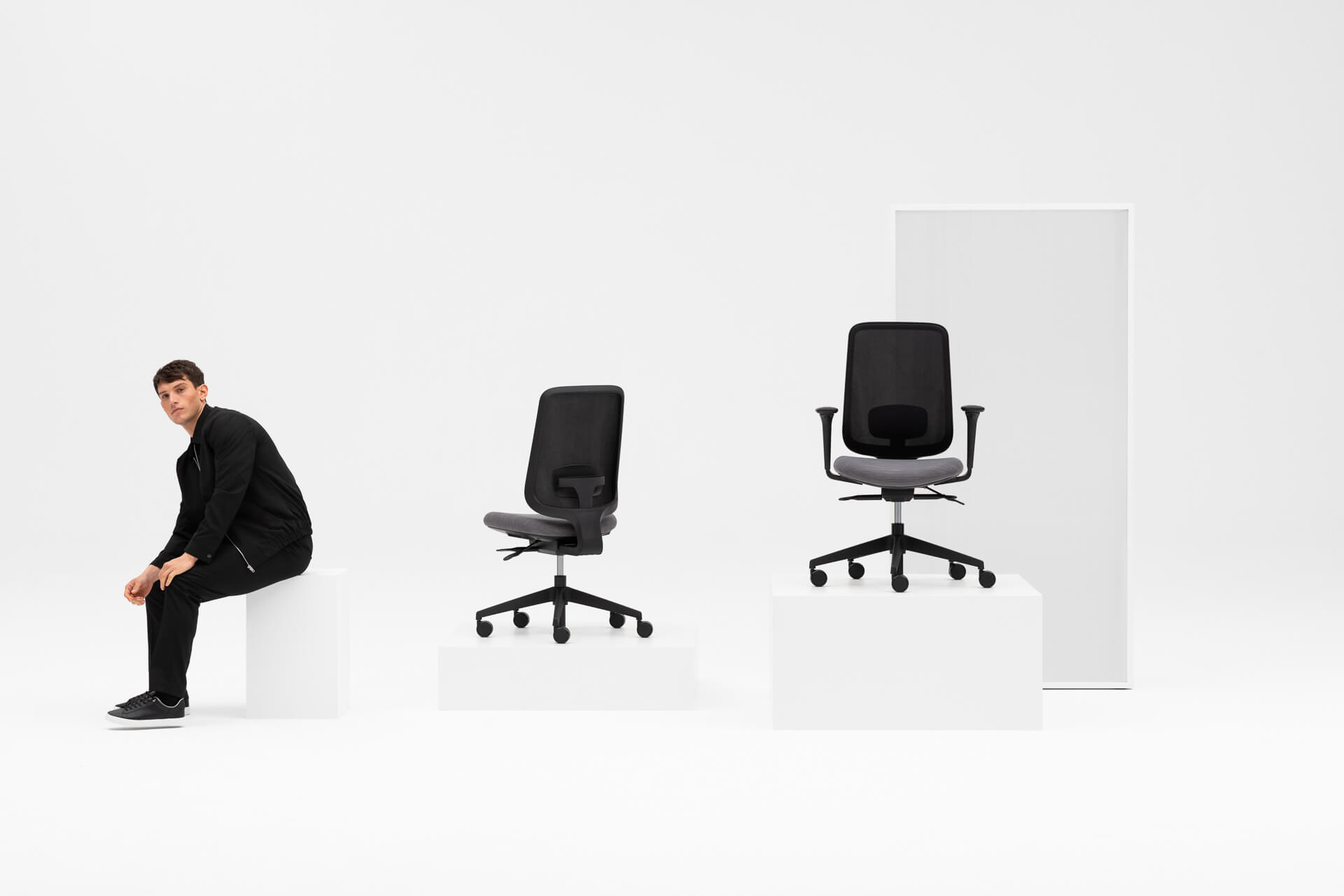 Side Shot Of A Person Sitting On A White Box With Two Other Boxes Next To Them With Task One Black Frame Office Chairs On Them