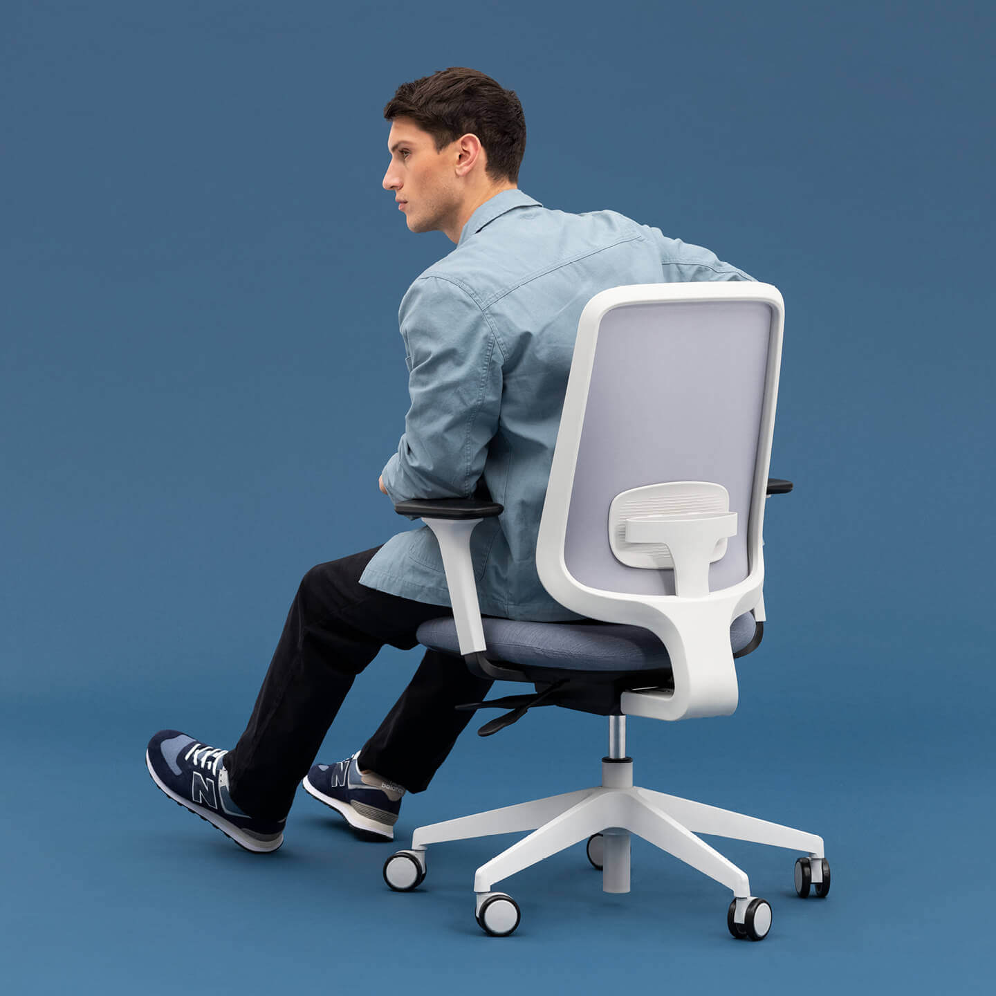 The Back Of A Model Wearing Different Shades Of Blue Sitting On A Task One Office Chair With Arms And Bluestone Seat