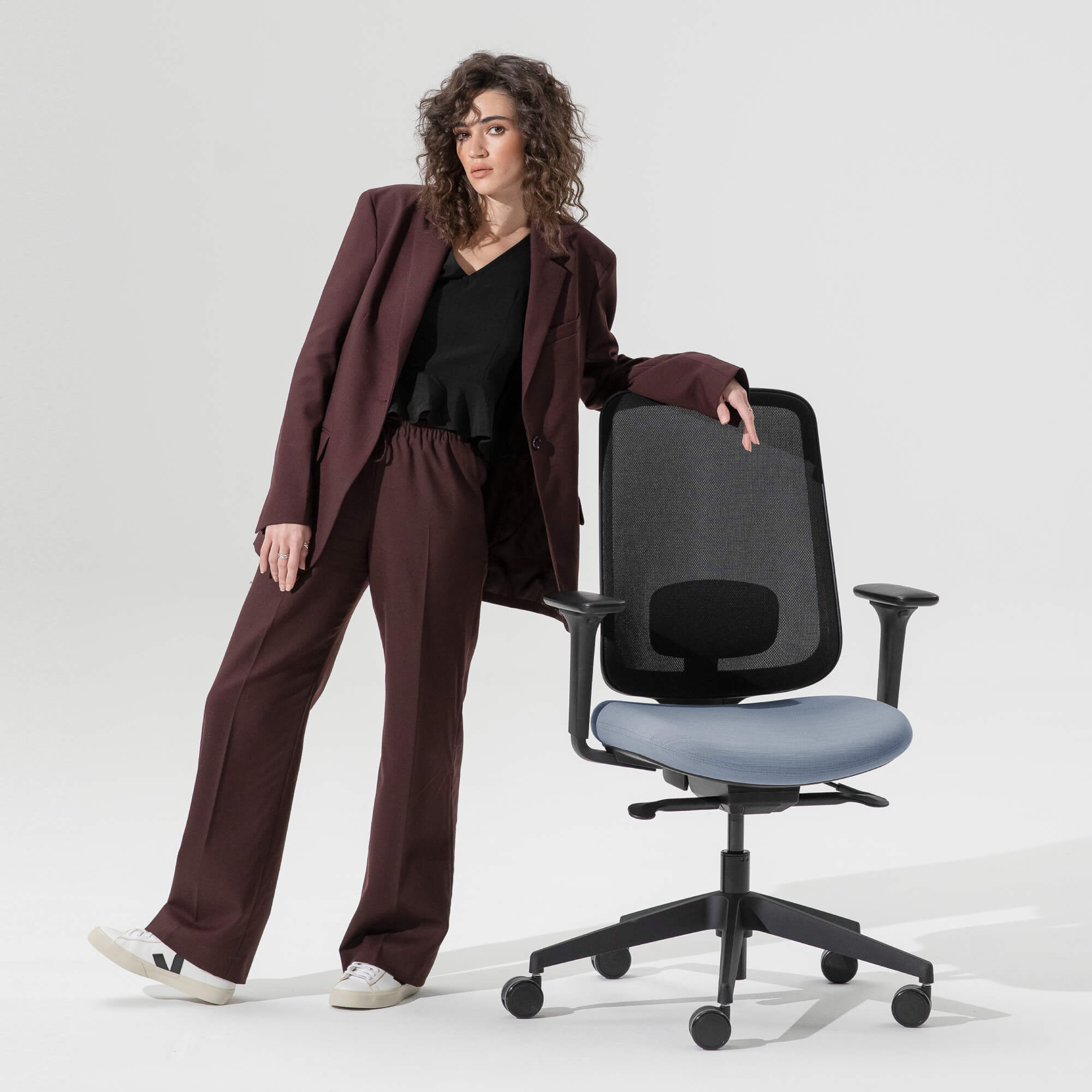 Person Leaning Against a Task One Black Frame Office Chair With Arms and Bluestone Seat