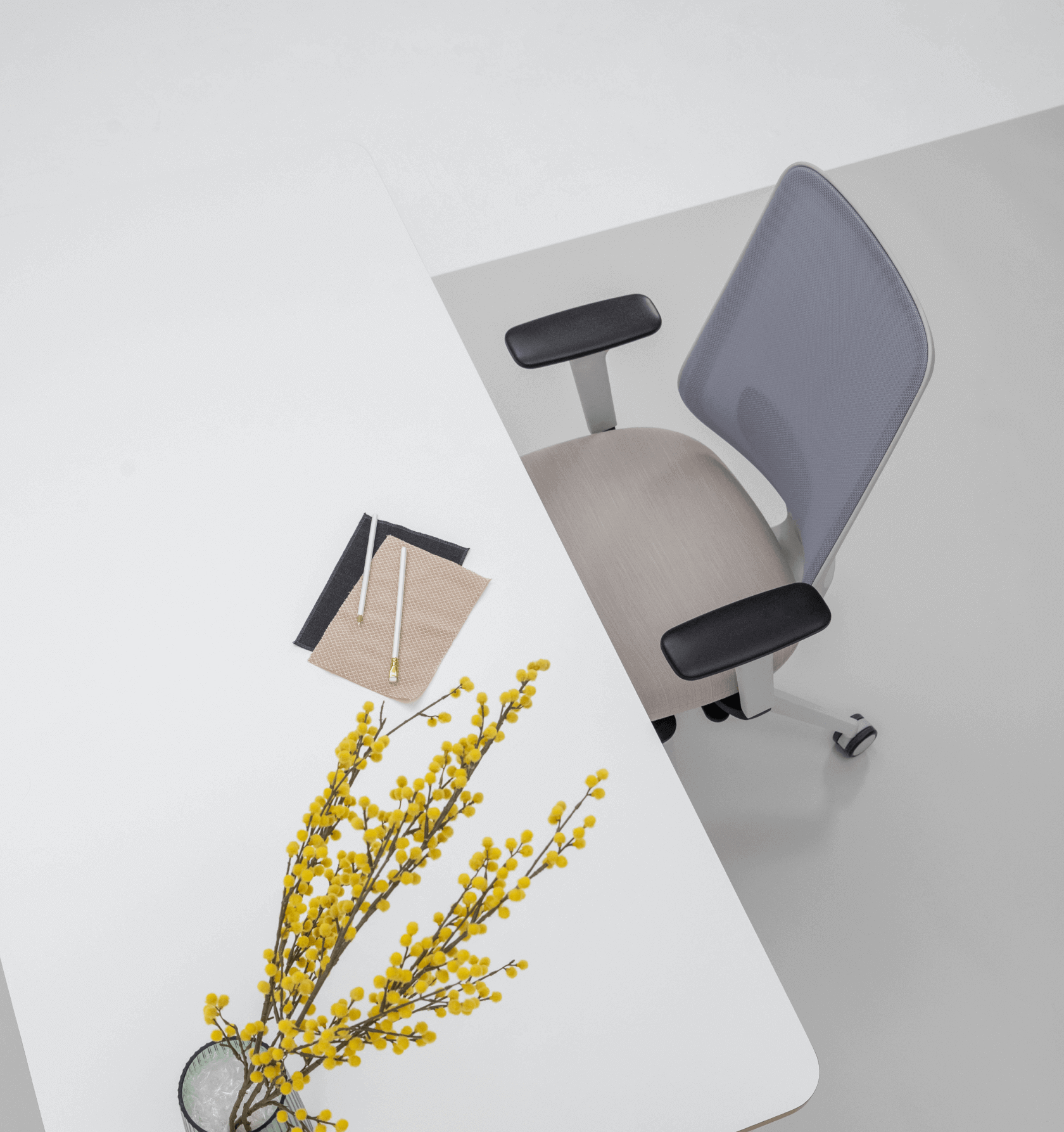 Birds Eye View of a Desk With a White Top and a Grey Frame Office Chair With Arms