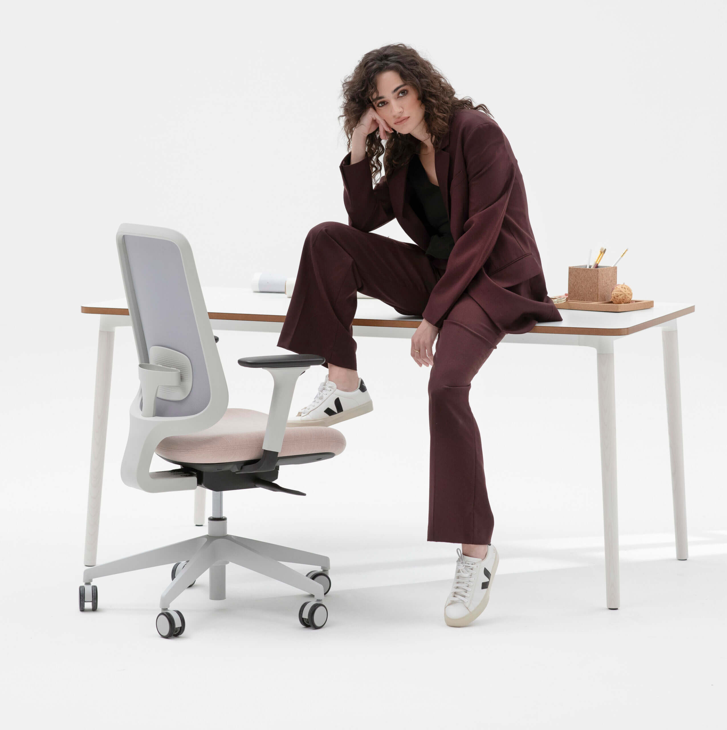 Person Sat On The Edge Of A Desk With Their Right Foot Placed On The Edge Of A Task One Grey Frame Office Chair